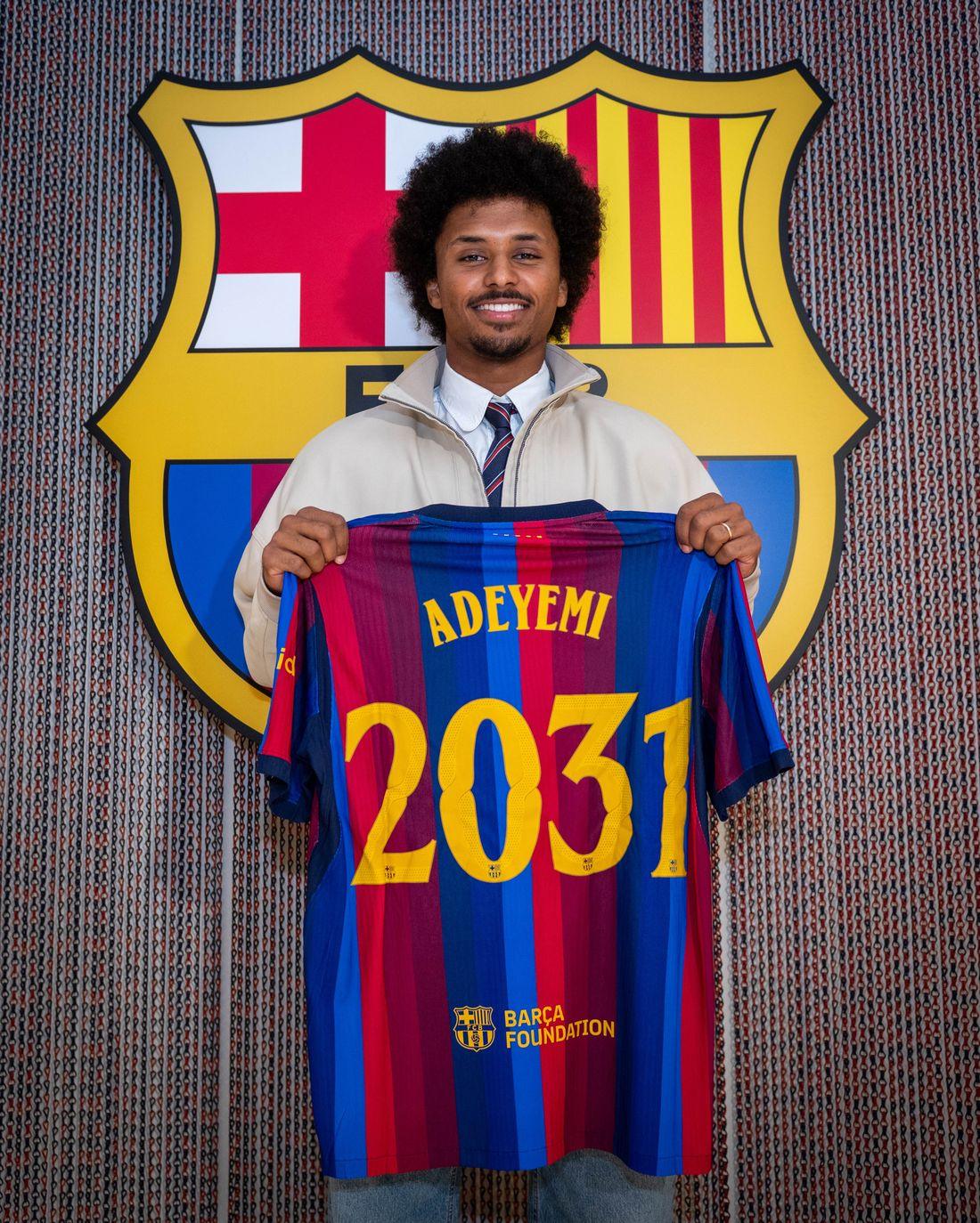 Karim Adeyemi holds up his Barcelona shirt in front of the club crest