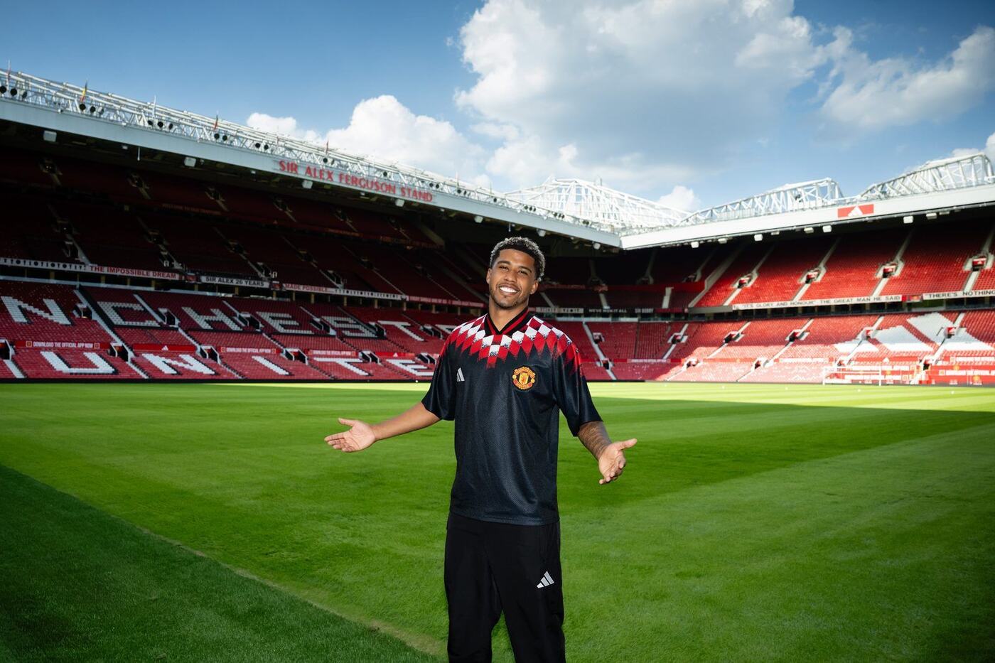 Andrey Santos poses in a Manchester United kit on the pitch at Old Trafford after completing his move from Chelsea